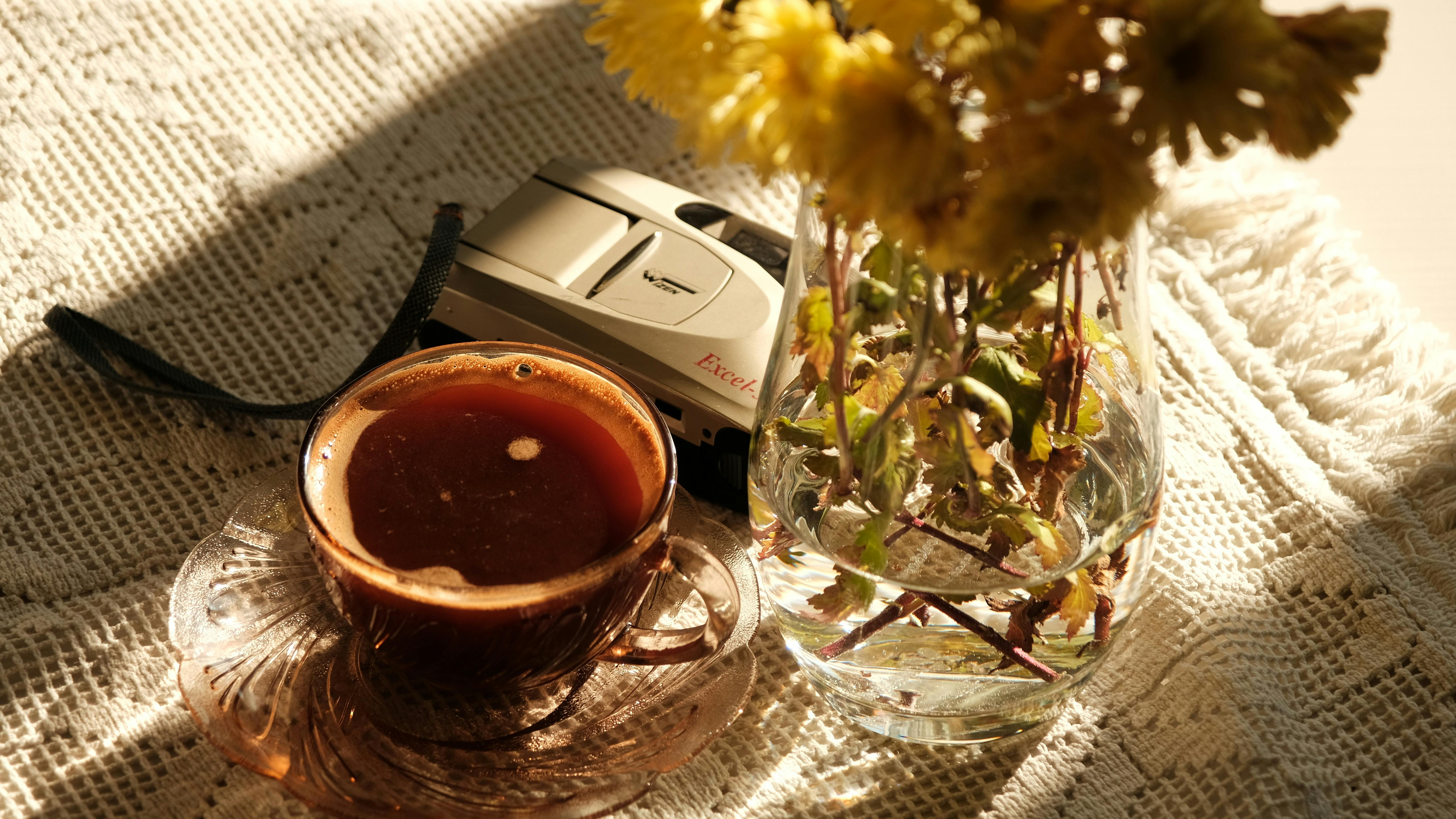 Kostenlos Eine friedliche Szene mit Kaffee, einer Vintage-Kamera und Blumen in warmem Licht. Stock-Foto