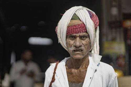 Free Elderly Rajasthani man wearing a traditional turban in a bustling street scene. Stock Photo