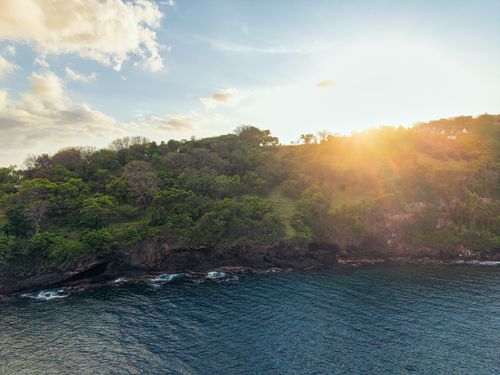 Free Captivating sunset over lush, green cliffs meeting the ocean in Bali, Indonesia. Stock Photo