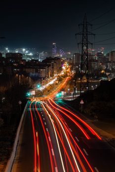 Urban cityscape at night showing vibrant light trails from traffic, creating dynamic movement.