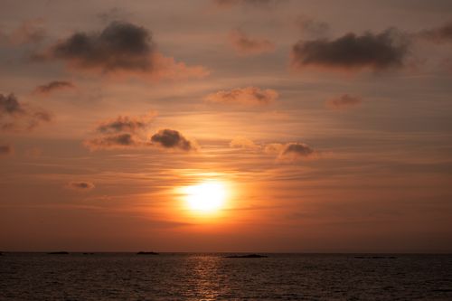 Free Peaceful sunrise view with orange hues and gentle clouds over the ocean. Stock Photo
