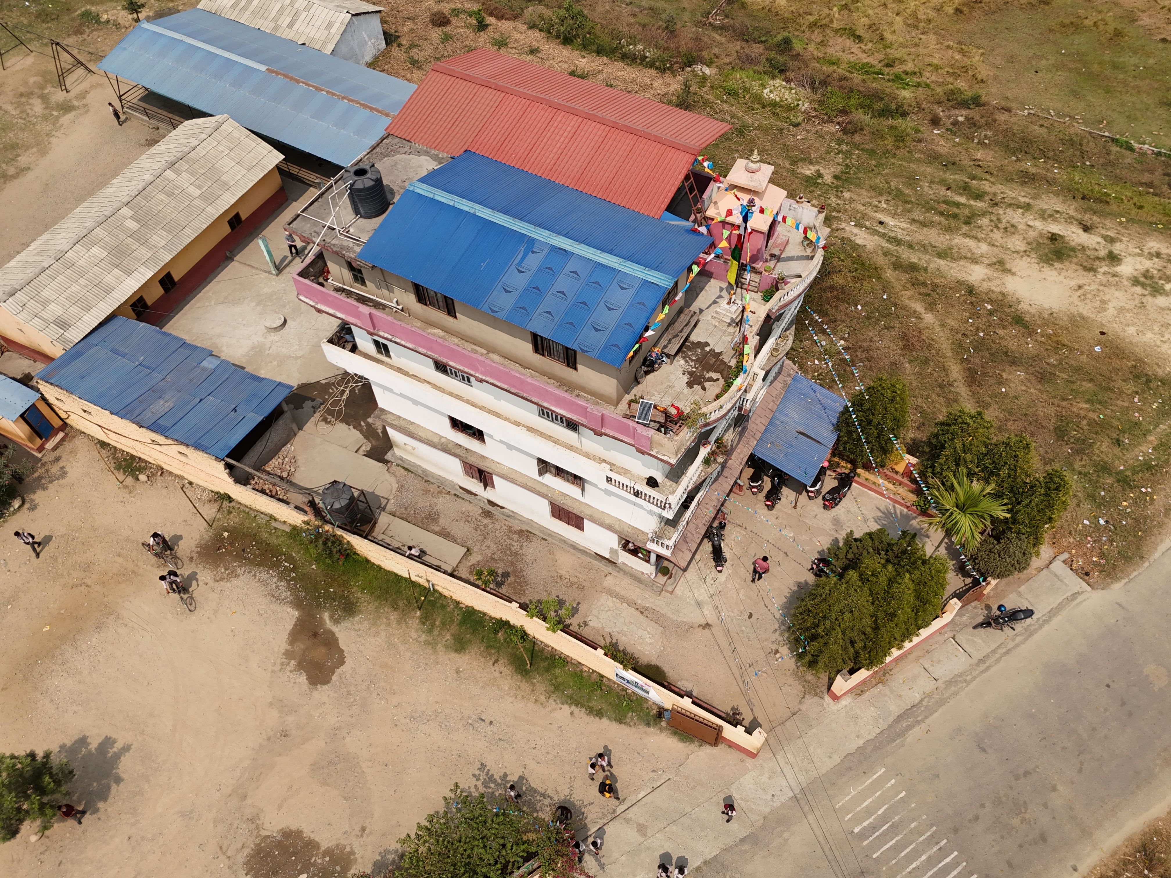 Amazing From Pokhara: Annapurna Base Camp (ABC) Helicopter Landing Tour Review 2026 - Aerial shot of a colorful multi-story building in a rural area of Nepal.