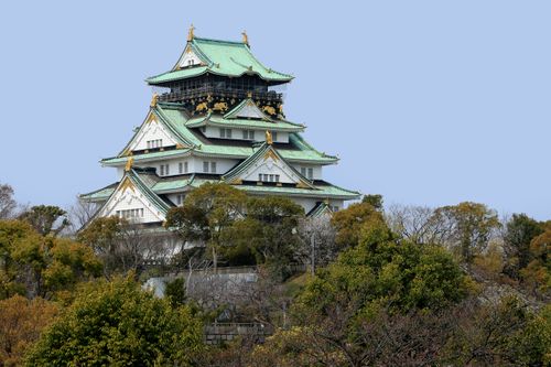 Free A stunning view of Osaka Castle surrounded by lush greenery under clear blue skies. Stock Photo