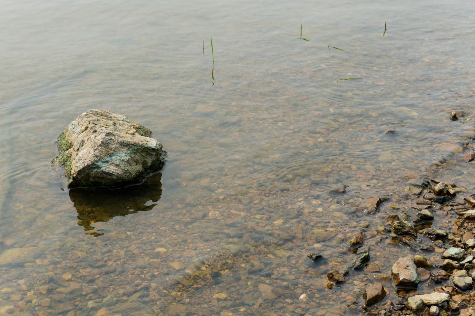 Rocher isolé dans une eau claire et peu profonde sur une rive de galets