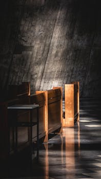 Dramatic light casts shadows on polished wood pews inside a quiet church.
