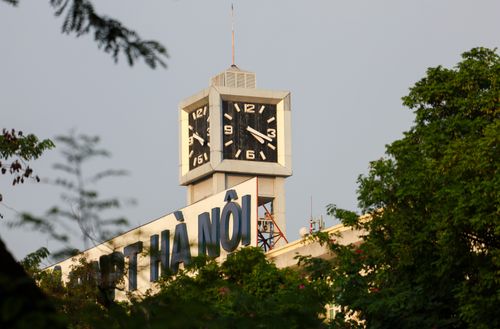 Free A beautiful view of the iconic clock tower in Hà Nội, Việt Nam, surrounded by lush greenery at sunset. Stock Photo