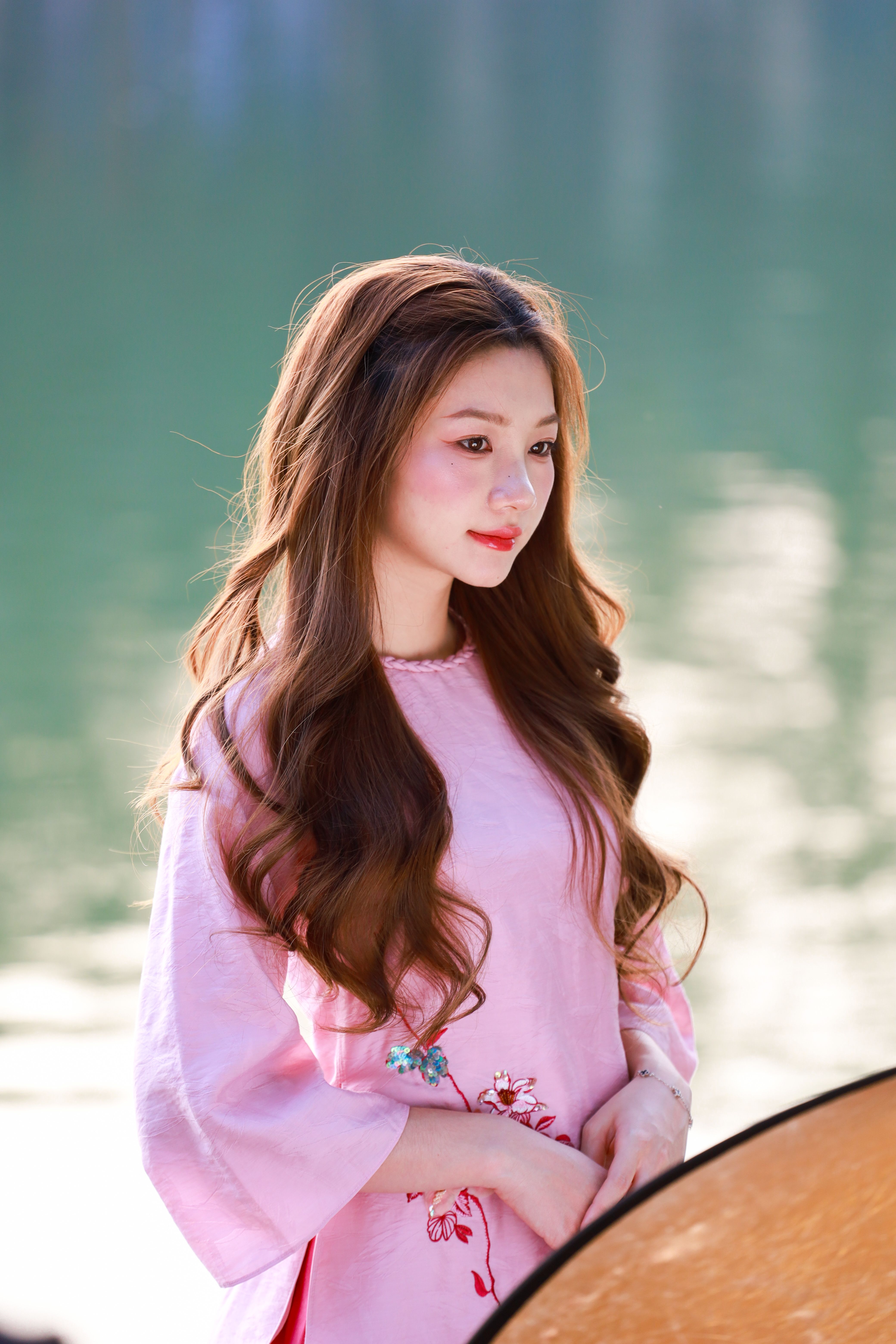A serene portrait of a young woman in traditional Vietnamese attire standing by a lake in Hanoi.