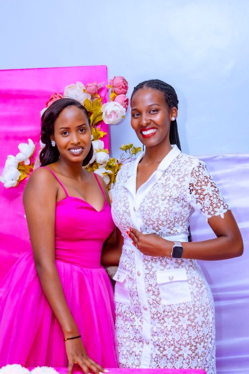 Free Two women posing at a pink-themed event, adorned with flowers and bright smiles. Stock Photo