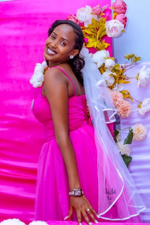 Free Beautiful bride in pink dress smiling at a vibrantly decorated wedding backdrop. Stock Photo