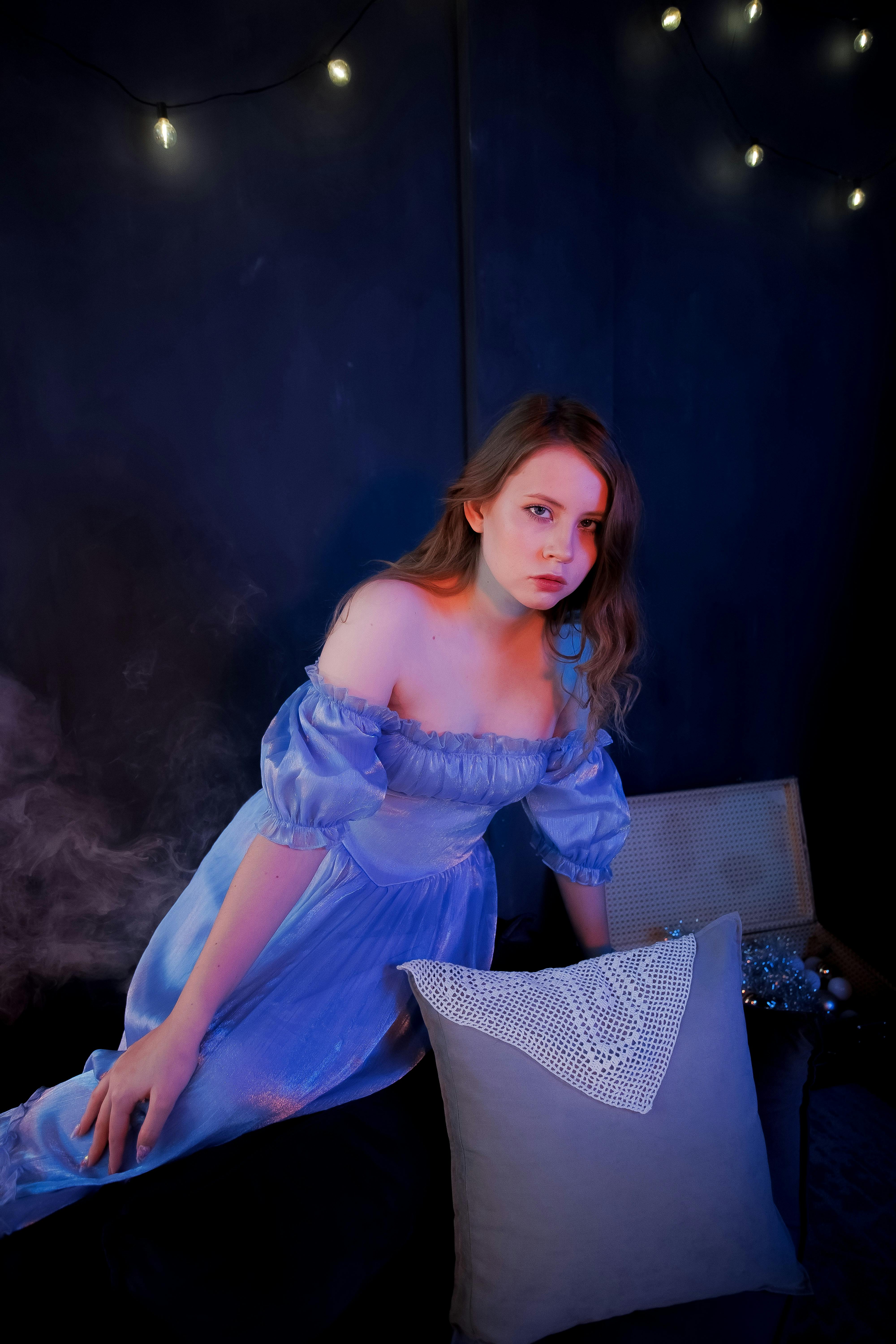 Moody portrait of a woman in blue dress with fairy lights creating a dreamy atmosphere.