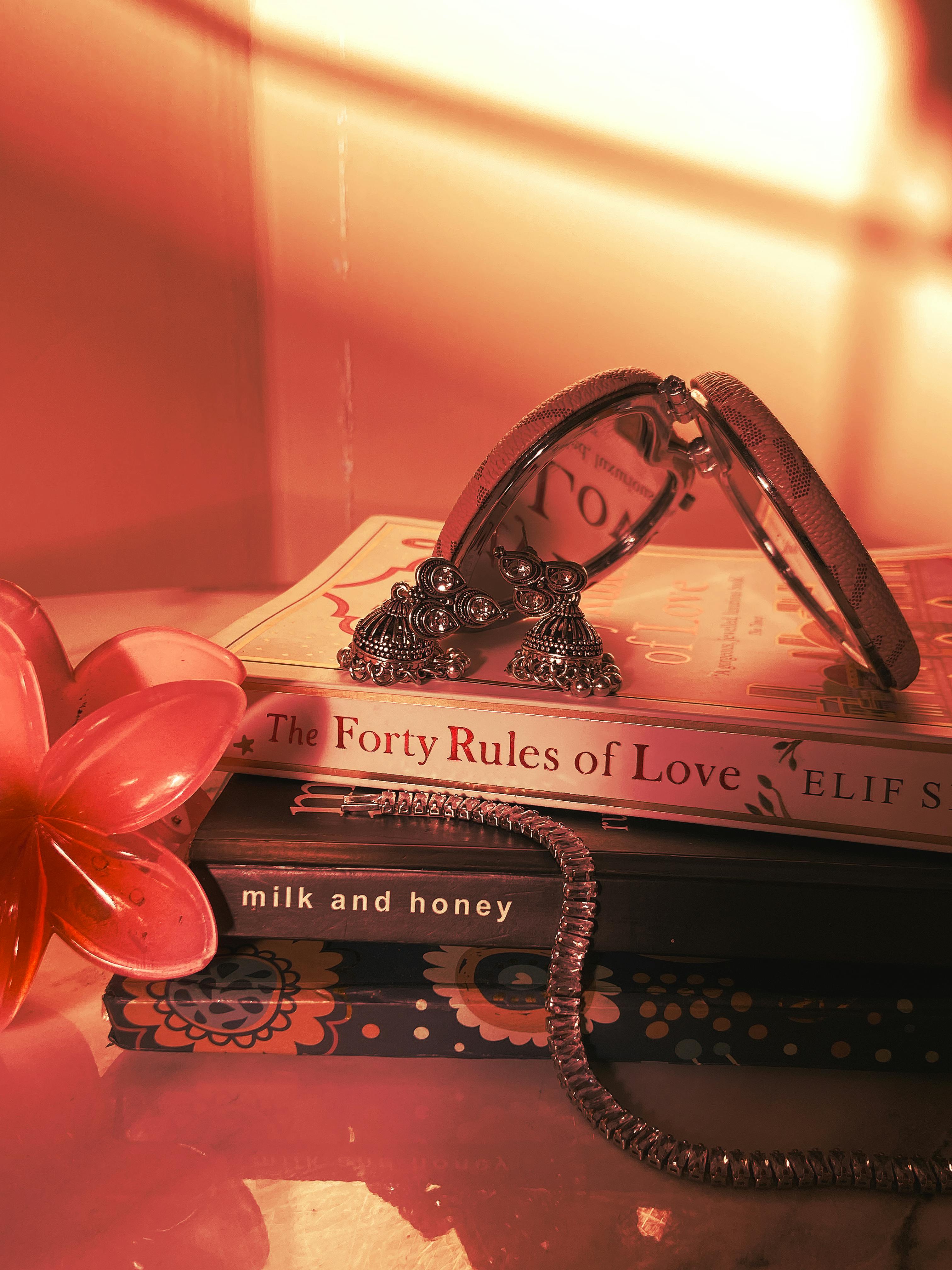 Warm-toned still life with books, jewelry, and vintage mirror.