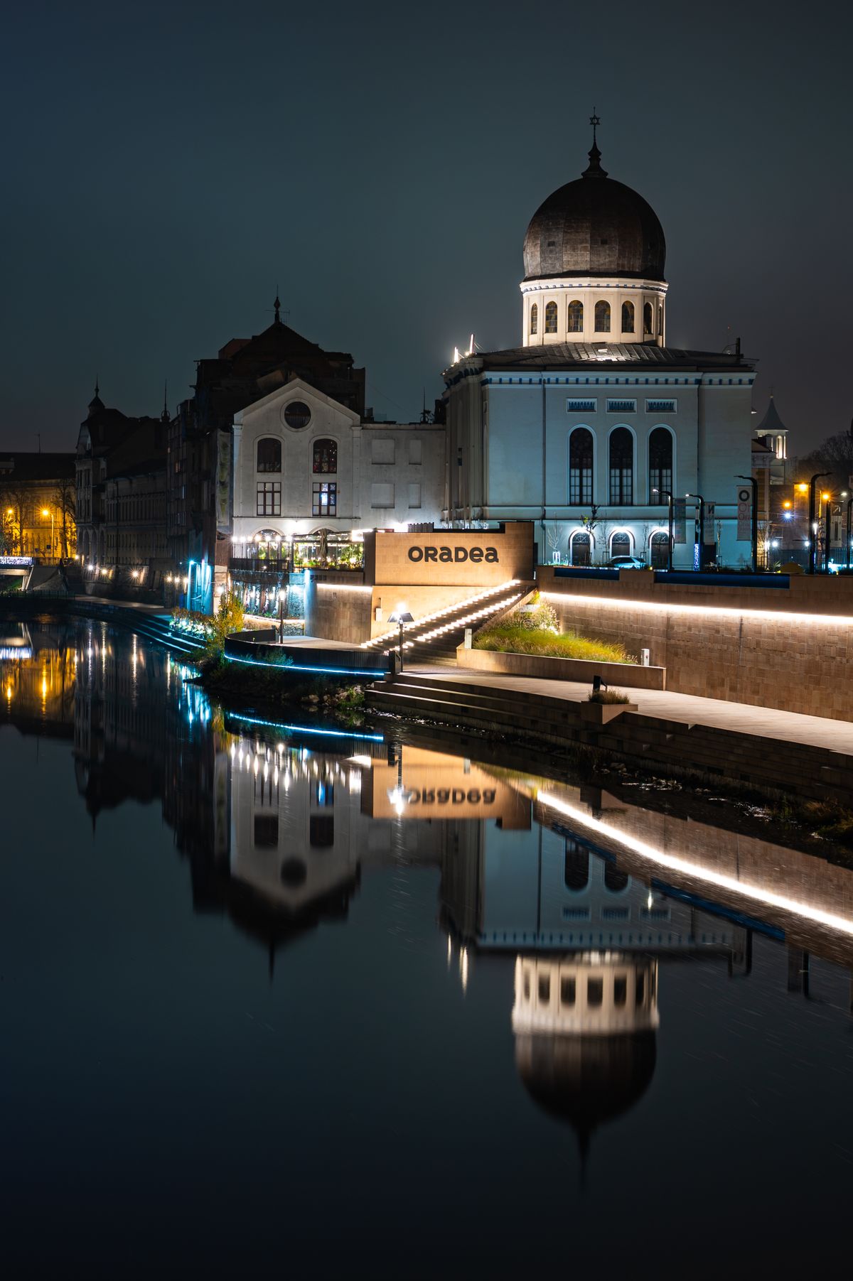 Unde te cazezi în Oradea - centrul iluminat noaptea, oglindit în Crișul Repede
