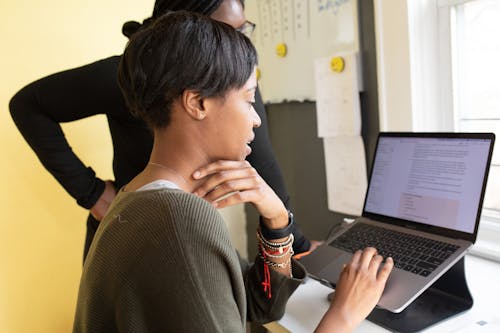 woman in a grey sweater working on a laptop