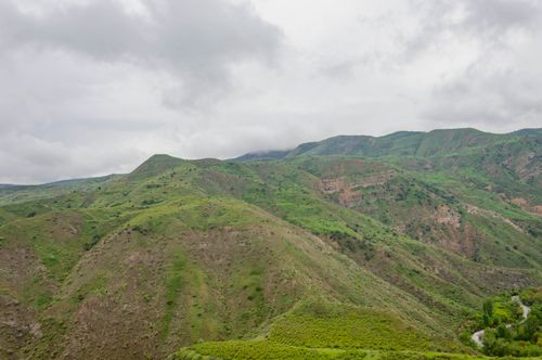 Free Stunning landscape of vibrant green hills beneath a cloudy sky, capturing nature's serenity and beauty. Stock Photo