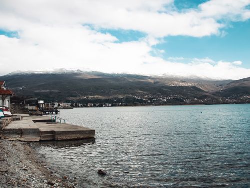 Free Peaceful lake with mountain backdrop and cloudy sky creating a serene landscape. Stock Photo