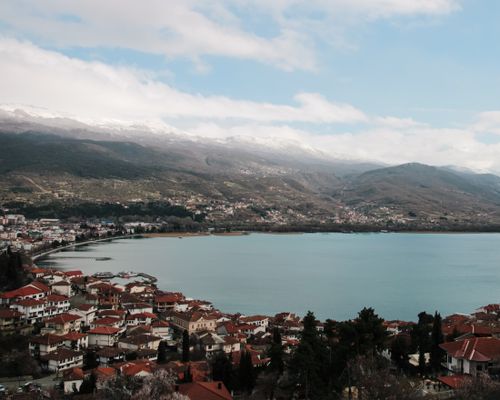 Free Aerial view of the picturesque Ohrid Lake with surrounding mountains and red rooftops. Stock Photo