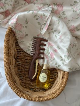 Aesthetic wicker basket with floral cloth, hair oil, and wooden comb.