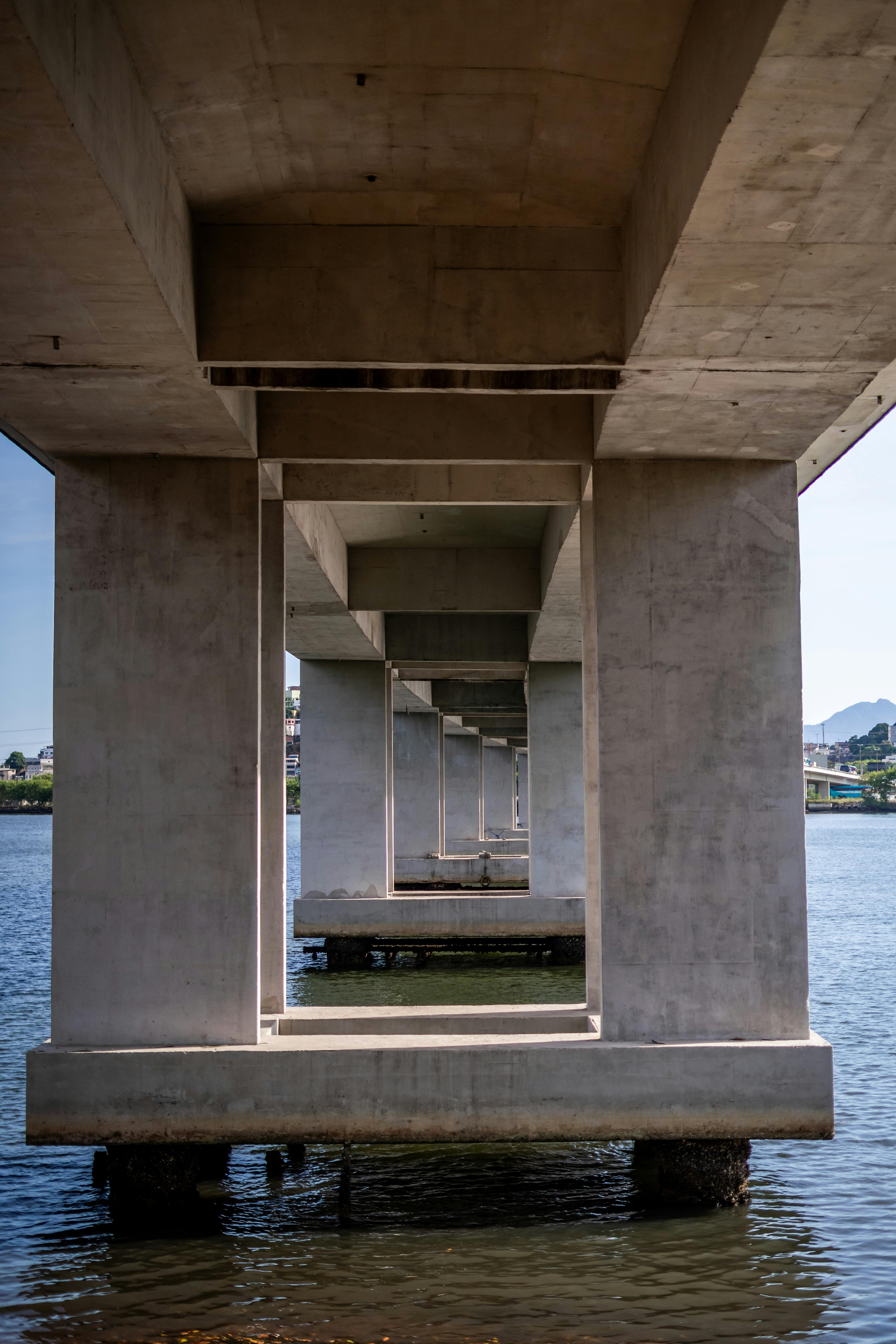 Symmetrical view of a concrete bridge over water, showcasing architectural geometry.
