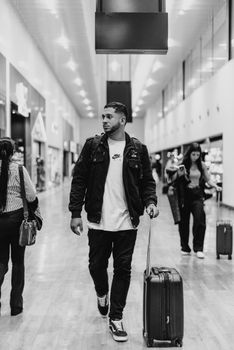 Man walking with luggage in a stylish airport terminal, capturing modern travel vibes.