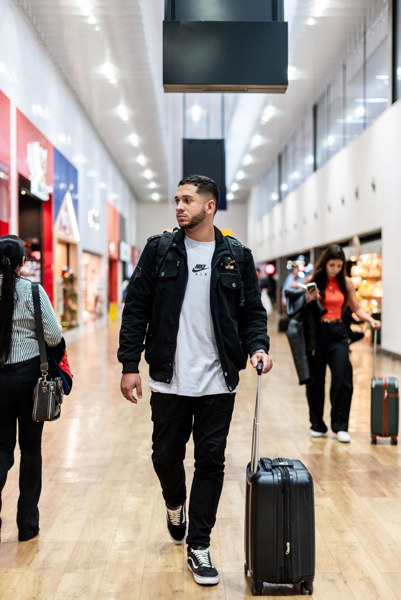 A traveller with a suitcase walking through a bright modern airport terminal