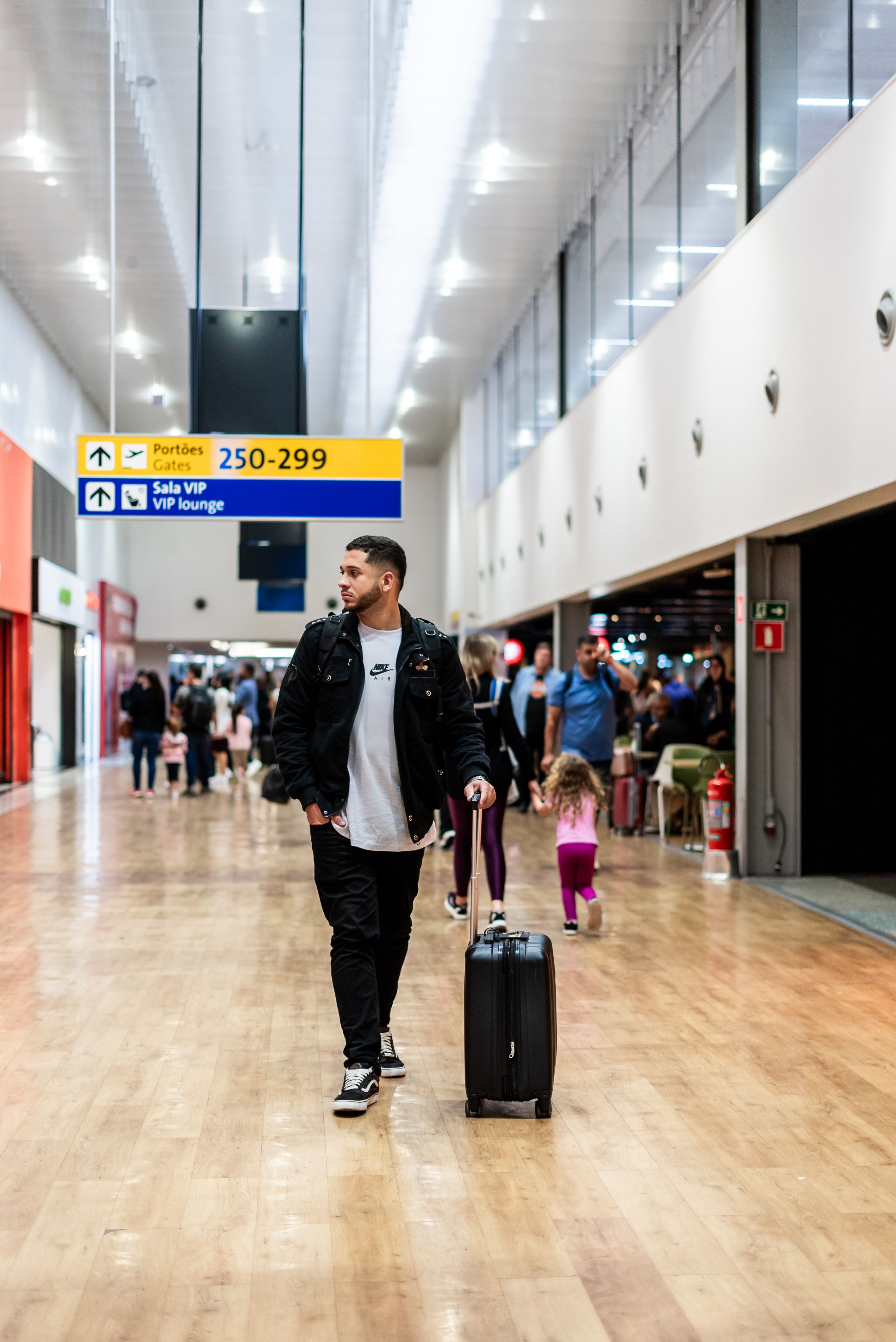 Traveler pulling luggage through a busy airport terminal, suitable for flights and logistics content.