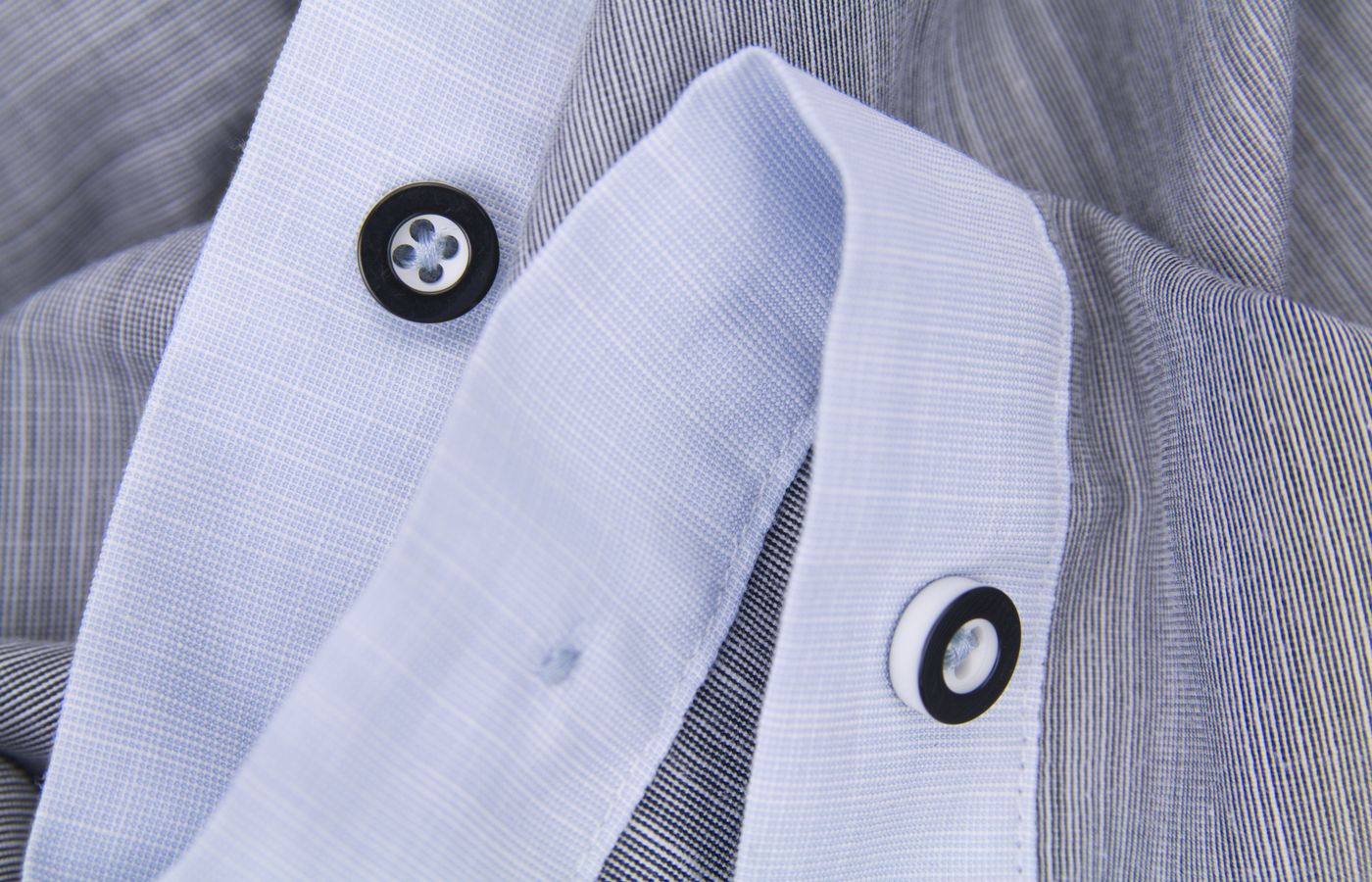 Detailed close-up of black and white buttons on a striped shirt showcasing fabric texture.