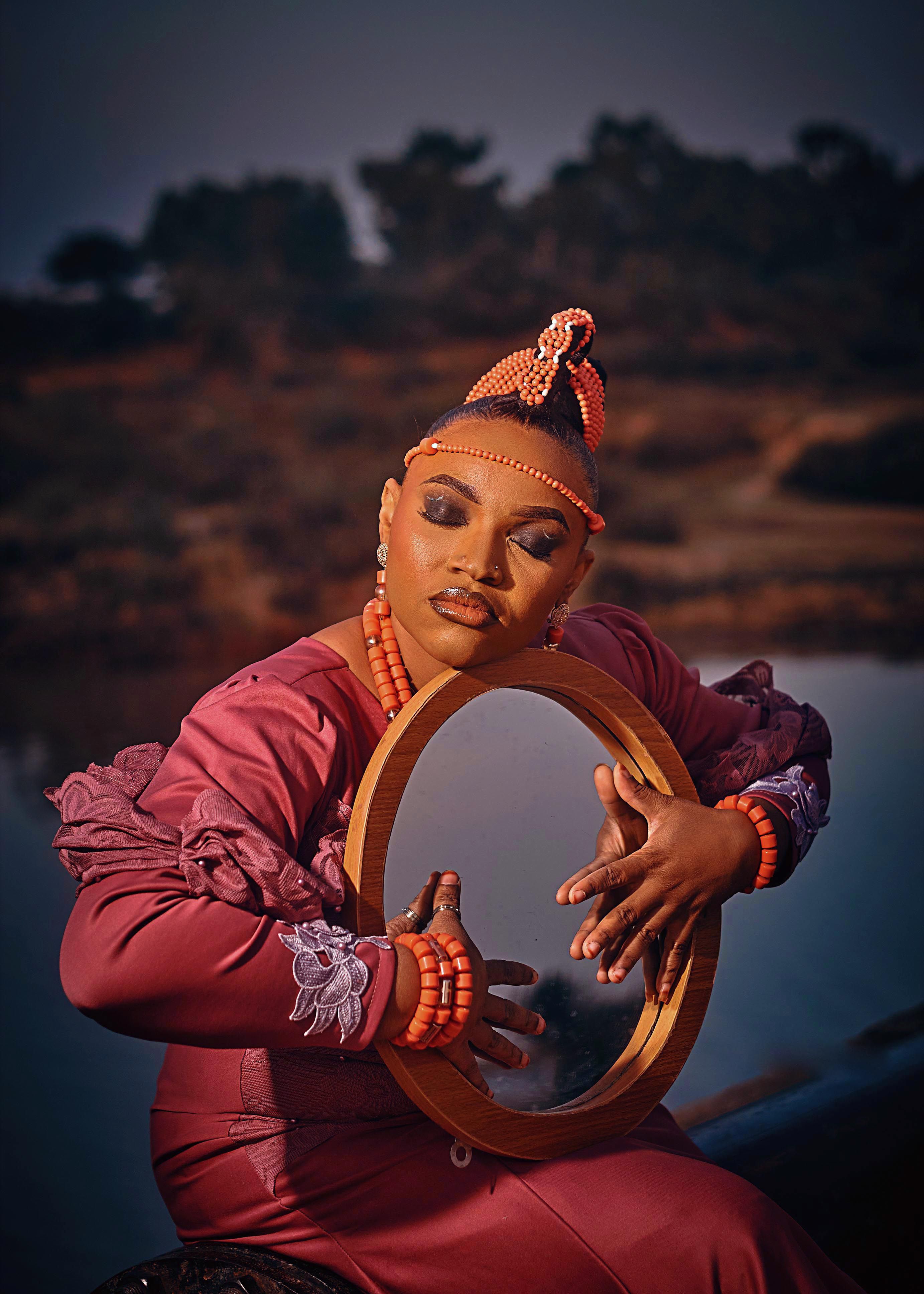 African woman in traditional attire holding a mirror, reflecting grace and culture.