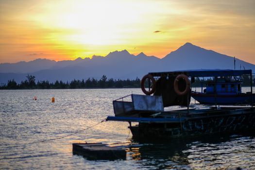 A tranquil morning scene capturing a boat and mountains during sunrise in Da Nang, Vietnam.
