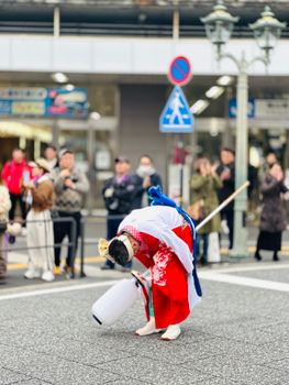A performer in traditional attire bows during a cultural street event in Fukuyama, Hiroshima.