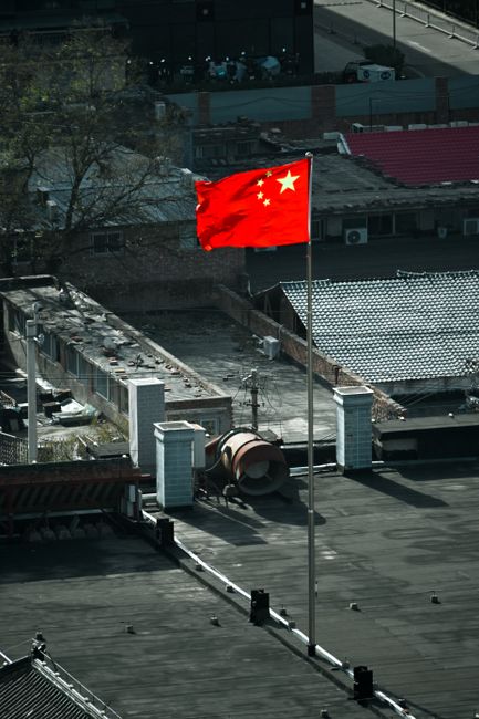 Fotomural Vista aérea de la bandera china en lo alto de un edificio en Beijing, China, simbolizando el orgullo nacional en medio del paisaje urbano.
