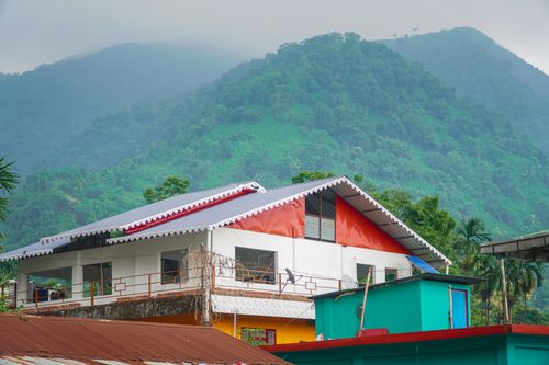 Free Colorful house nestled against misty green hills, showcasing natural serenity and vibrant architecture. Stock Photo
