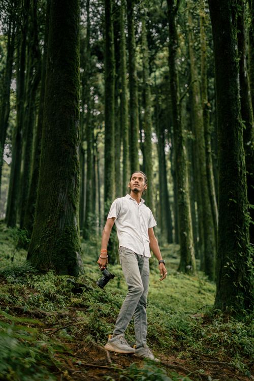 Free A man in a white shirt holding a camera explores a lush forest in Darjeeling, India. Stock Photo