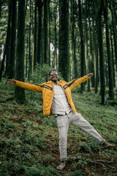 A cheerful man in a yellow jacket explores lush forests in Darjeeling.