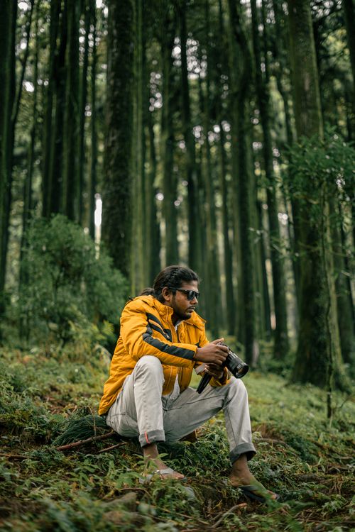 Free A photographer in a yellow jacket captures nature's beauty in a lush forest in Darjeeling, India. Stock Photo