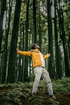 A man in a yellow jacket embraces the lush forest of Darjeeling, India.