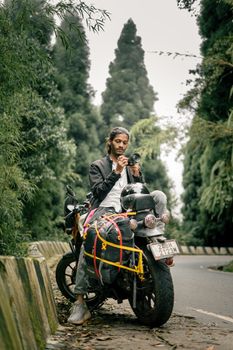 Young traveler on a motorcycle enjoying the lush greenery of Darjeeling's forests.