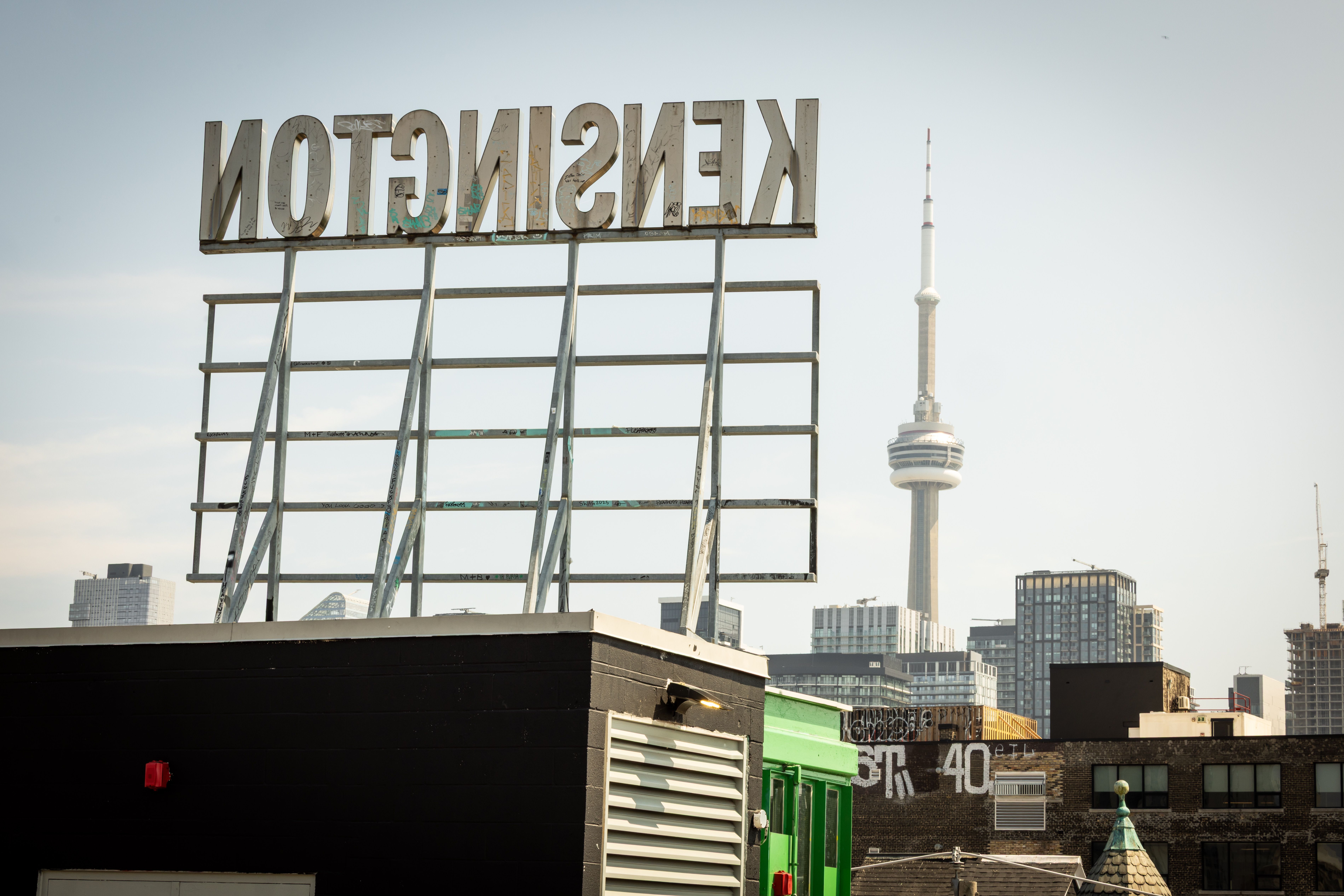Skyline view of Toronto featuring the CN Tower from Kensington's rooftop under a clear sky.