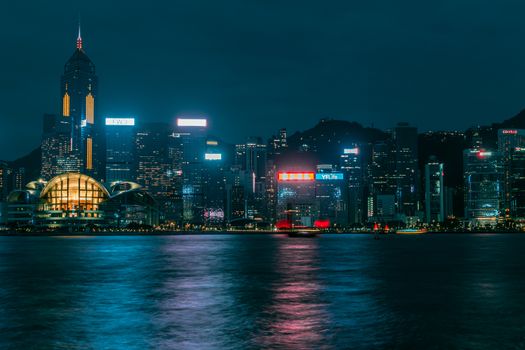 Dramatic Hong Kong skyline illuminated at night, reflecting on Victoria Harbor.