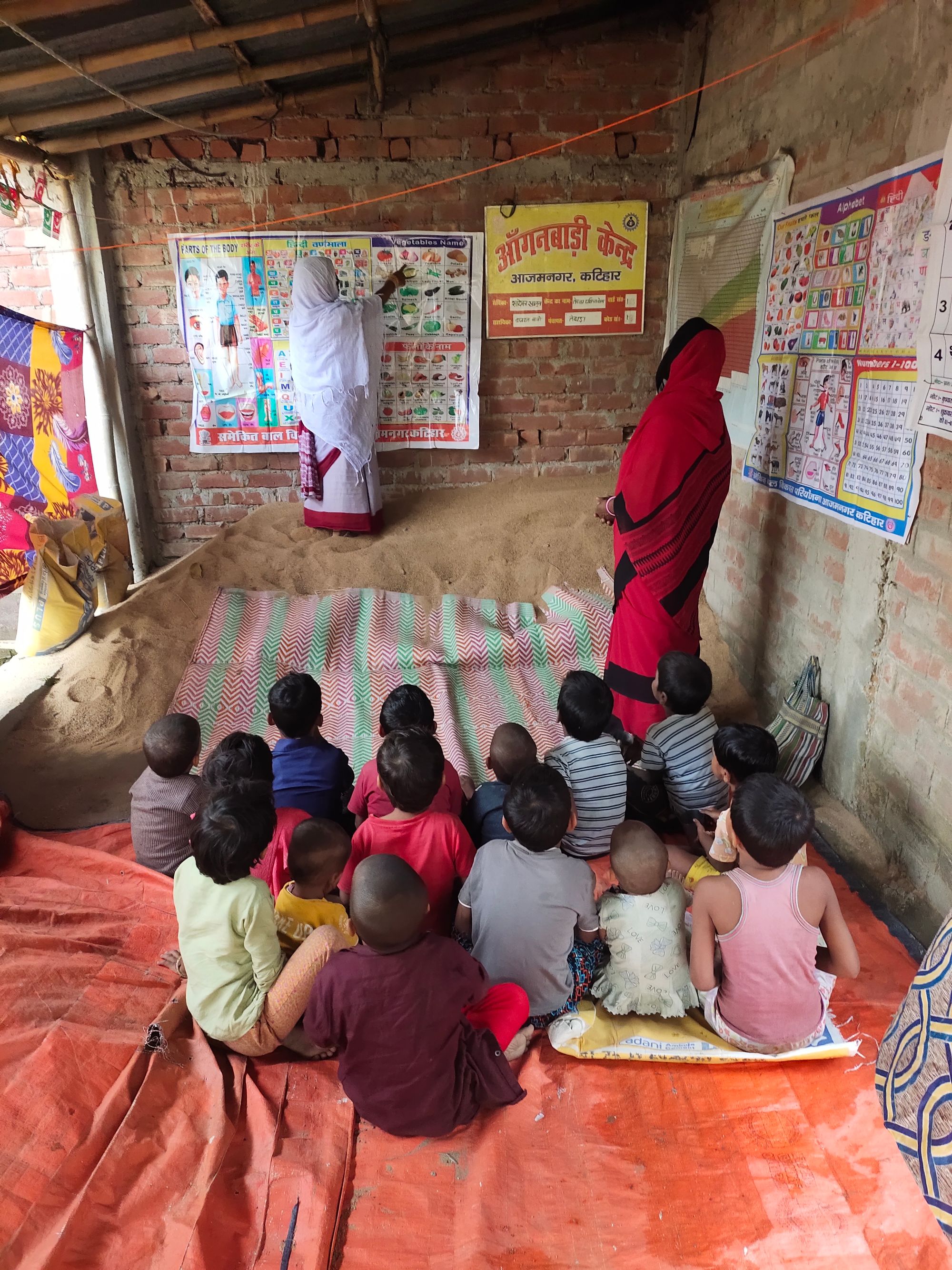 Children seated on the floor of a rural government school classroom in Kishanganj, Bihar, listening to a lesson