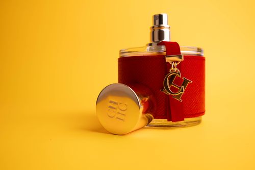 Free Stylish red perfume bottle with gold detailing on a bright yellow backdrop, ideal for luxury advertising. Stock Photo