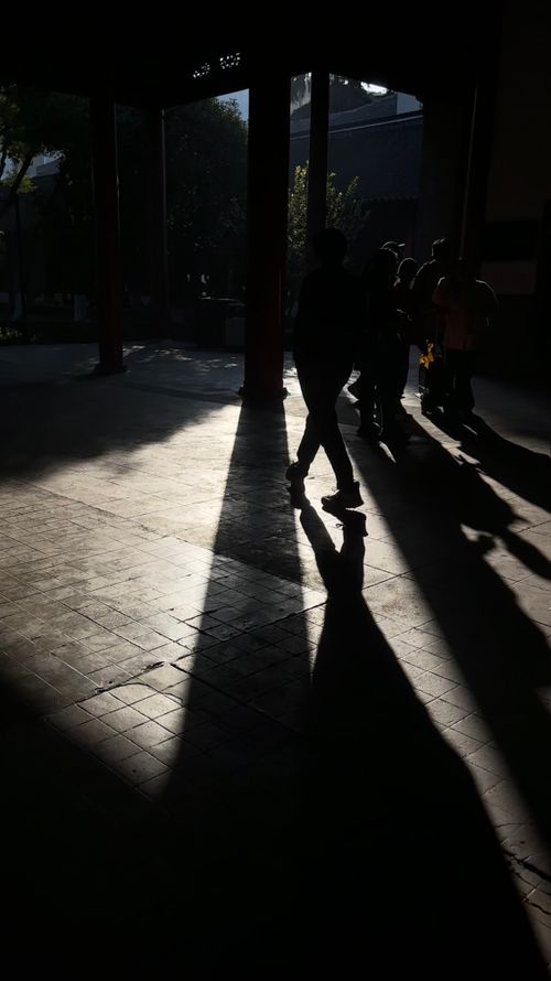 Free Silhouetted figures under an archway with elongated shadows in dramatic sunlight. Stock Photo