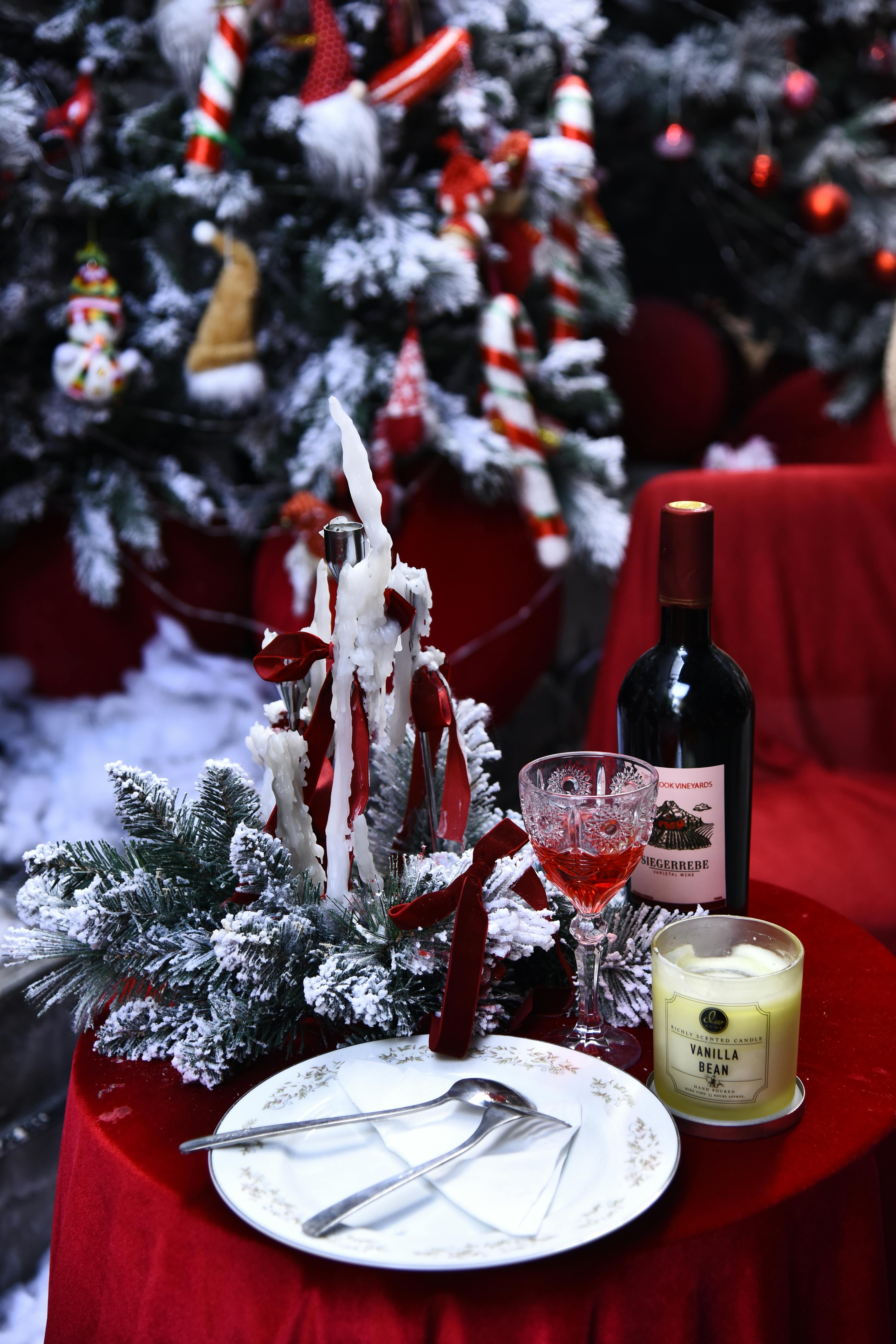 Cozy Christmas table setup with wine, candles, and decorations.