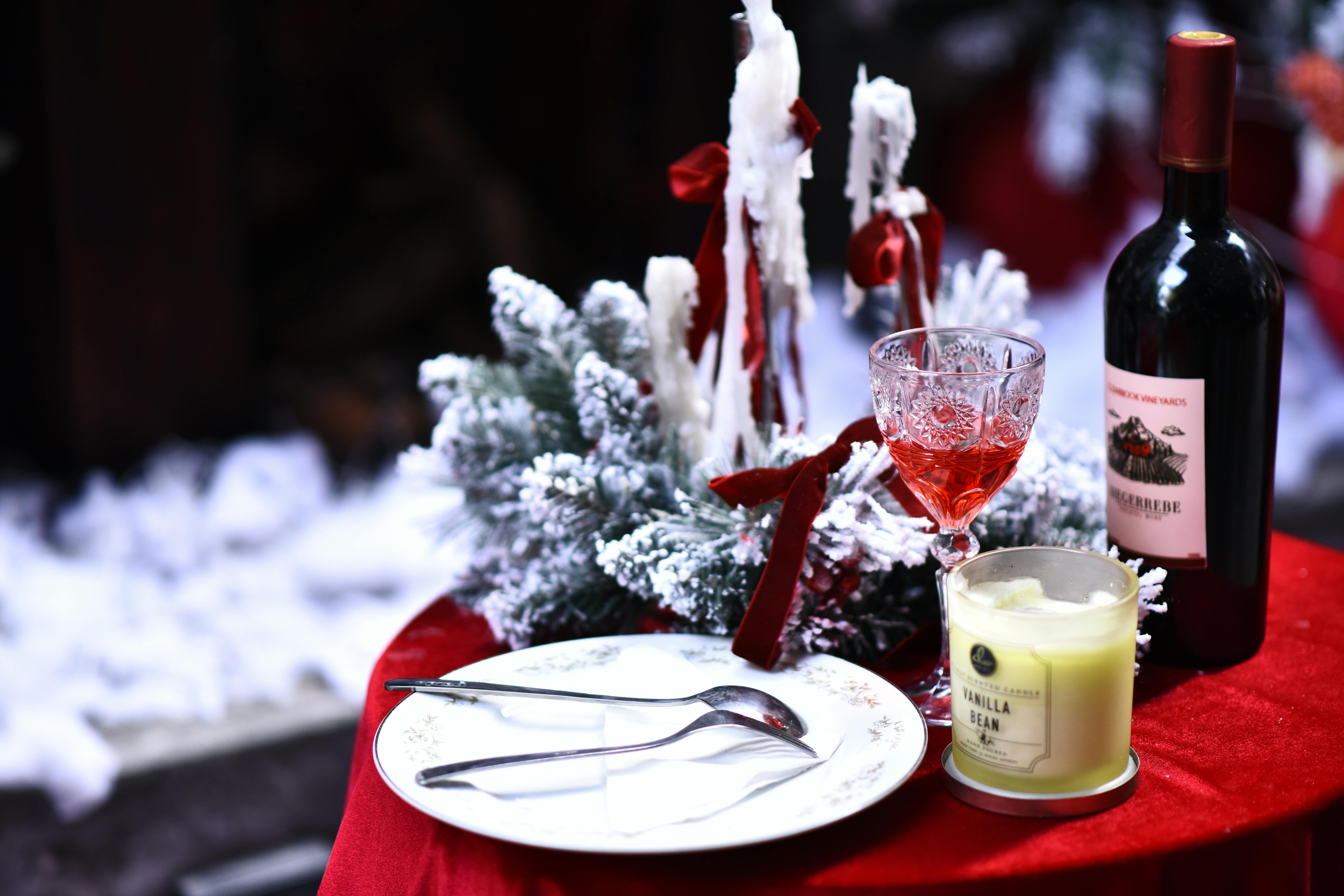 Elegant holiday table setting with wine, candle, and festive decorations, perfect for winter celebrations.