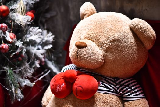 A large teddy bear in a festive setting with Christmas decor and ornaments.