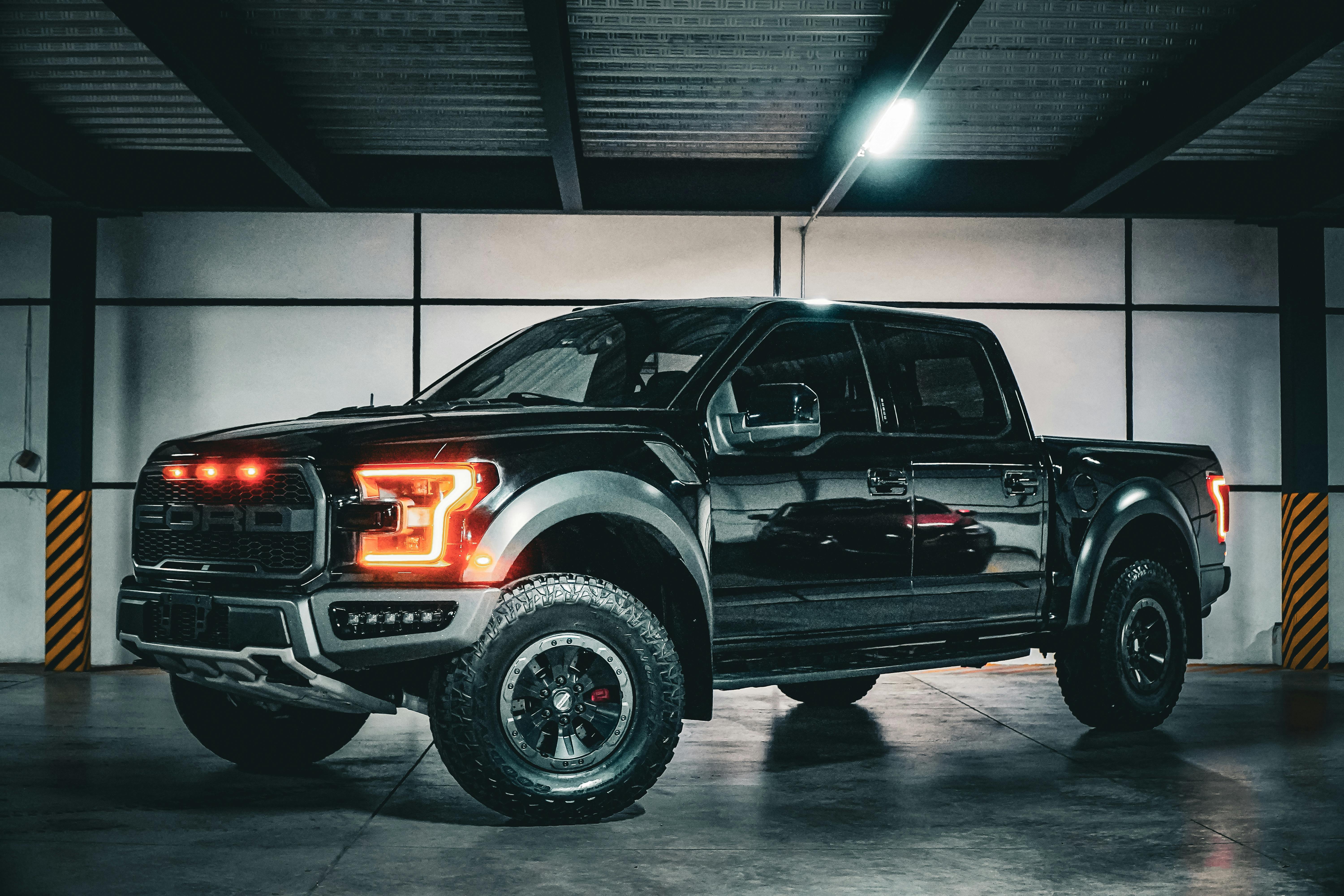 Bold black pickup truck with illuminated lights in an industrial garage.