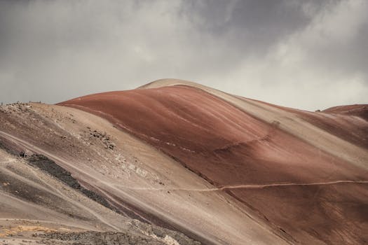 在戏剧性的多云天空下，红色沙丘的景观令人惊叹，捕捉到了大自然宁静的美丽