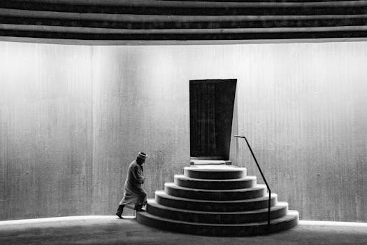 A person ascends circular stairs in a black and white mosque interior in İstanbul, Türkiye.