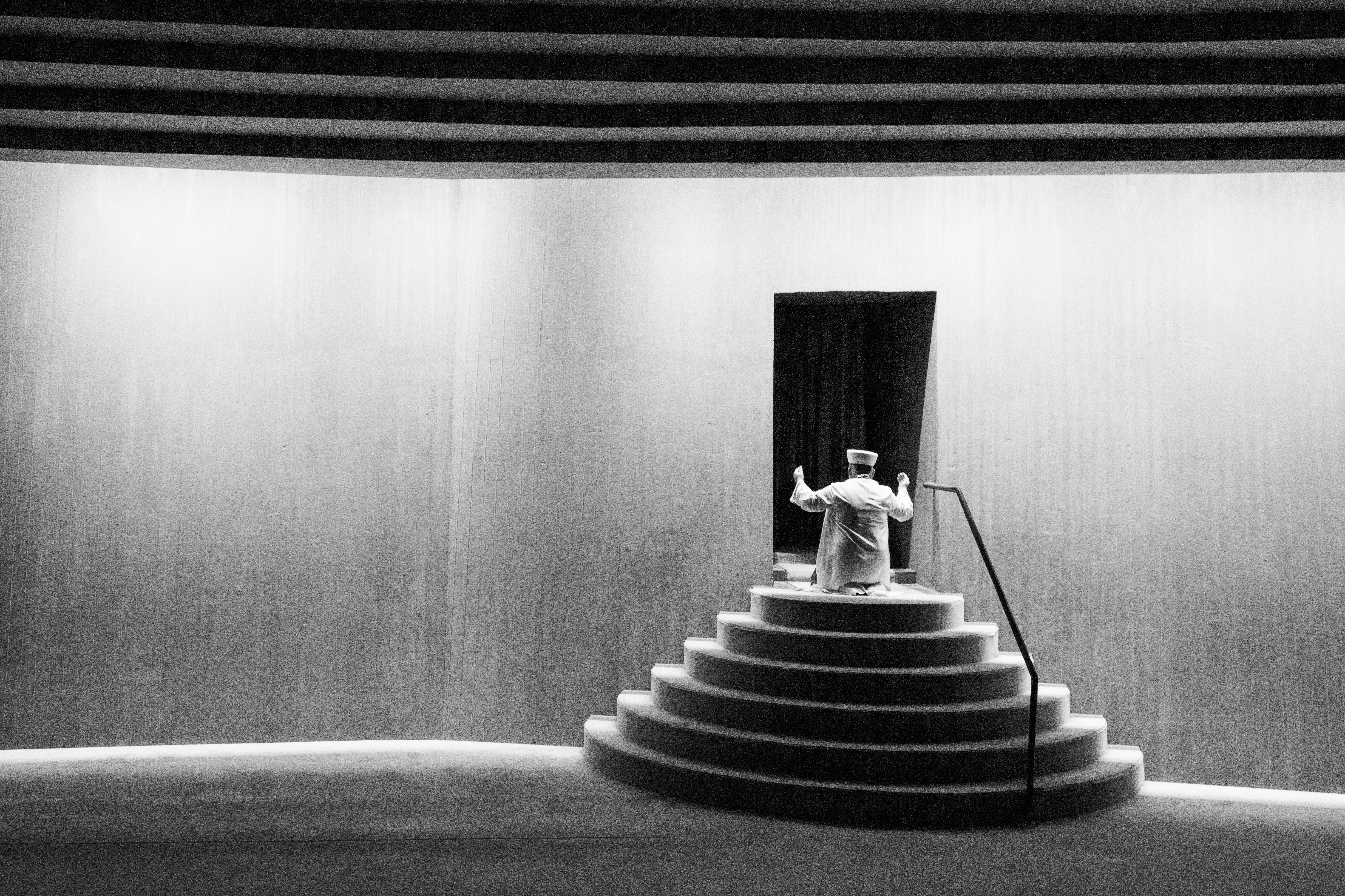 Ücretsiz İstanbul'daki bir caminin merdivenlerinde duran bir imamı, çarpıcı ışık ve gölge oyunlarıyla yakalayan siyah beyaz bir fotoğraf. Stok Fotoğraflar