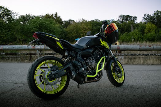 A sleek sport motorcycle with vibrant neon accents parked outdoors on a road at dusk.