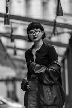 Black and white portrait of a fashionable woman in an urban environment.